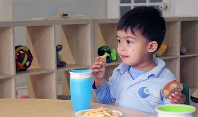 young boy eating a snack at daycare